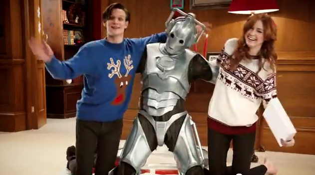 Doctor Who's Matt Smith (The Doctor) and Karen Gillan (Amelia Pond) wearing their Christmas sweaters. No Christmas sweater for the Cyberman?
